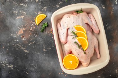 Fresh raw duck with orange thyme and spices on a dark background. Culinary cooking. banner, menu, recipe place for text, top view,
