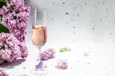 Gül şarabı ve leylak çiçekleri. Yaz kutlaması, düğün kartı, davetiye konsepti. Uzun pankart biçimi.