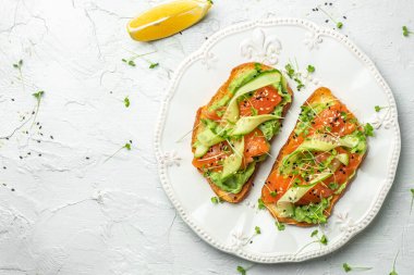 Tuzlu somon, avokado ve taze sebzeli sandviç. Lezzetli kahvaltı ya da atıştırmalık, temiz yemek, diyet, vejetaryen yemek konsepti. en üstteki görünüm
