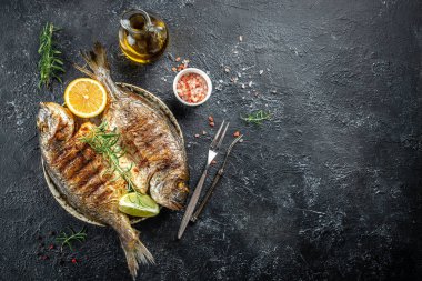 Fırında balık dorado. Koyu bir arka planda kızartılmış deniz kepeği ya da dorada balığı. en üstteki görünüm.
