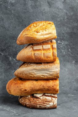 Bir dilim Craft ekmeği. Ev yapımı fırın. Koyu arka planda farklı ekmek türleri. dikey görüntü. Üst Manzara. metin için yer,