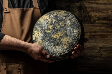 cheesemaker mele hands holding wheel hard cheese,