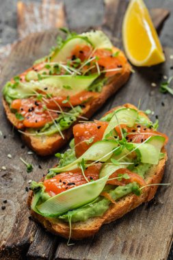 Tuzlu somon, avokado ve taze sebzeli sandviç. Lezzetli kahvaltı ya da atıştırmalık, temiz yemek, diyet, vejetaryen yemek konsepti. en üstteki görünüm