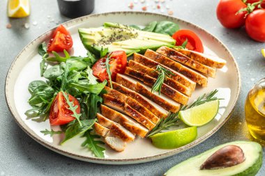 Taze yeşil salata ızgara tavuk filetosu, domates, avokado, açık arkaplanda limon. Diyet Konsepti. Üst görünüm kopyalama alanı,
