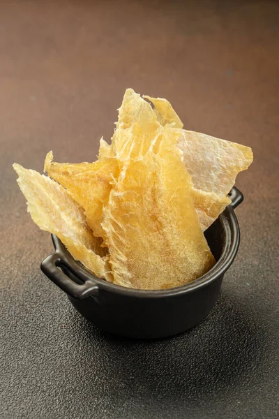 Bira için atıştırmalıklar, ahşap tabakta kurutulmuş balık karışımı. Koyu arkaplanda kurutulmuş balık sucuğu eti carpaccio. metin için yer, üst görünüm.