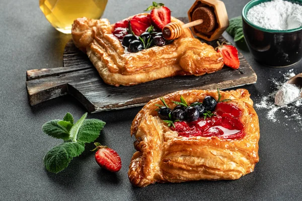 danish pastry with strawberry and honey on a dark background. banner, menu, recipe place for text, top view.