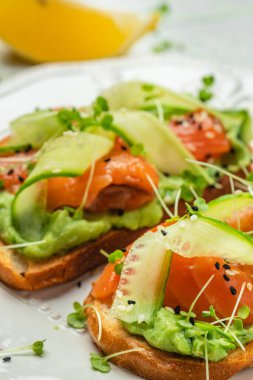 İki tost, tuzlanmış somon, avokado ve taze yeşillikler. Süper yiyecek konsepti. Sağlıklı, temiz yemek. Vejetaryen ya da glütensiz diyet. en üstteki görünüm.