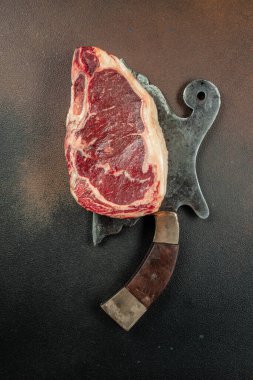 New York bifteği, tuz ve biberiyeli, koyu arka planda çiğ mermer sığır filetosu, dikey görüntü. Üst Manzara. metin için yer,
