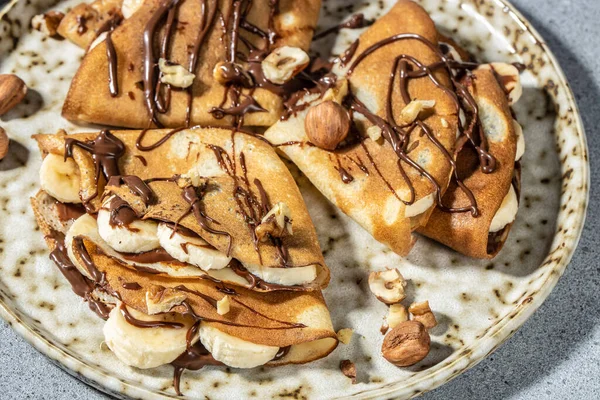 Homemade thin crepes with chocolate spread and hazelnuts for breakfast or dessert. banner, menu, recipe place for text, top view.