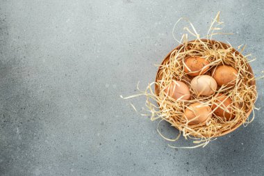 Saman yuvasında kahverengi yumurtalar. Tavuk yumurtası. Tarım, biyolojik ve eko tarım kavramı, biyolojik gıda ürünleri. afiş, menü, tarif, üst görünüm.