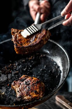 Karanlık bir arka planda lezzetli etli biftek. dikey görüntü. Üst Manzara. metin için yer.