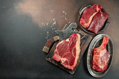 Siyah taşlı arka planda et bifteği ve bıçak arasında bir kemik. Çiğ et. Uzun afiş biçimi. Üst görünüm, metin için yer, üst görünüm,
