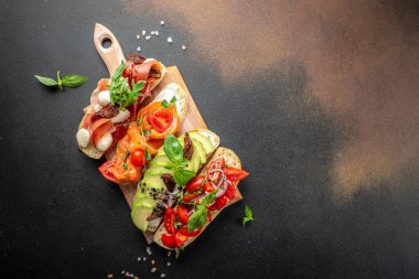 Tahta bir tahtada jambon, somon, domates ve avokado soslu bruschetta seti, pankart, menü, yazı için tarif yeri, üst görünüm.,