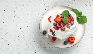 Açık arkaplanda krem şantili mini pavlova pastaları ve taze böğürtlenler, uzun afiş formatında. en üstteki görünüm,