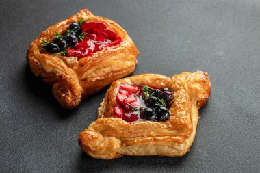 Koyu arkaplanda taze böğürtlenli puf böreğinden yapılmış küçük bir açık turta, yemek tarifi geçmişi. Kapat.,