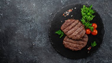 Koyu arkaplanda ızgara hamburger köfteleri, uzun afiş formatında. en üstteki görünüm.