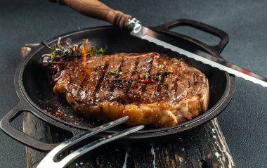 Izgara biftek, kırmızı şarap, otlar ve baharatlar. Fotokopi alanı olan siyah bir arka planda orta pişmiş biftek..