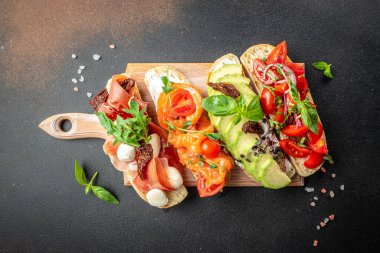 Tahta bir tahtada jambon, somon, domates ve avokado soslu bruschetta seti, pankart, menü, yazı için tarif yeri, üst görünüm.,