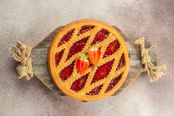 Homemade whole strawberry jam tart with jam on a wooden board, banner, menu, recipe top view,
