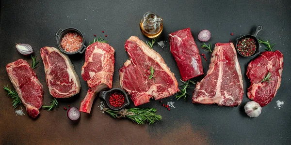 Black angus prime meat set for grilling with fresh herbs, spices. Long banner format. top view.