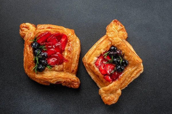 square fruit filled French puff pastry dessert with berries on a dark background. banner, menu, recipe place for text, top view.