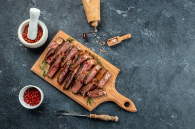 Biberiye ve baharatla dilimlenmiş orta pişmiş ızgara biftek ve kırmızı şarap..