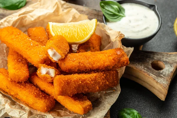 Baked Fish Sticks served with lemon and tartar sauce. Food recipe background. Close up.