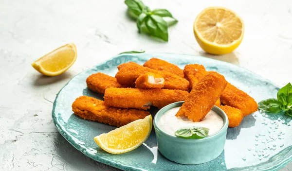 Crumbed fish sticks served with lemon and tartar sauce. Long banner format. top view.