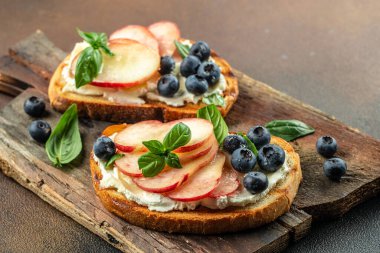 Şeftalili tost, ricotta, ahşap bir tahtanın üzerinde yabanmersini. Yemek tarifi geçmişi. Kapat..