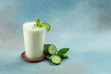 Mavi arka planda salatalıklı ev yapımı yoğurt Ayran, kilo vermek için temiz yemek. metin için yer.