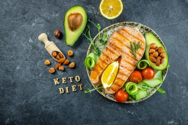 Avokado ve taze sebze salatasıyla ızgara somon bifteği. Keto diyet konsepti sağlıklı yiyecekler, sağlıklı yağlar, kilo vermek için temiz yiyecekler. en üstteki görünüm.