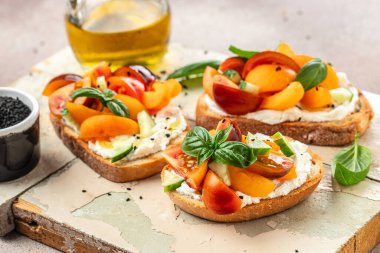 Tost, aperatif, bruschetta, krem peynirli sandviç, şeftali, domates ve yeşil fesleğen yaprağı, sağlıklı ve dengeli yeme kavramı. metin için yer, üst görünüm,