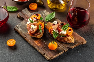 Prosciutto ile nefis crostini, kiraz domatesleri ve fesleğen yapraklı krem peynir kırmızı şarap ile servis edilir..