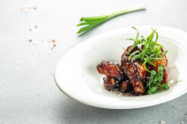 Kızarmış tavuk kanadı ve susam tohumlu barbekü sosu.,