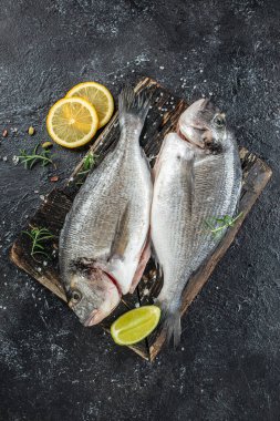 Koyu arkaplanda limonlu iki dorado balığı. dikey görüntü. Üst Manzara. metin için yer,