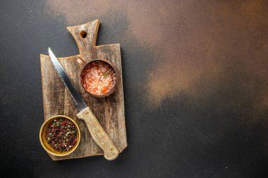 Yemek pişirmek için kesme tahtası. Baharat ve otlarla siyah beton üzerinde ahşap kesim tahtası. Menü, tarif modeli, afiş arkaplanı.