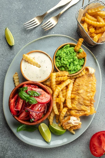 British traditional fish and potato chips served with mashed peas, vegetable salad, tartar sauce, vertical image. top view. place for text,