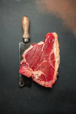 Siyah taşlı arka planda et bifteği ve bıçak arasında bir kemik. Çiğ et. metin için yer, üst görünüm.