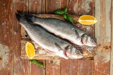 Kesme tahtasındaki çiğ deniz kabuğu balığı, baharatlar, ahşap arka planda otlar. Üst Manzara. metin için yer.