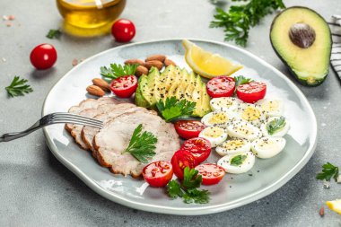 Keto diyet yemeği. Avokado tabağı, haşlanmış bıldırcın yumurtası, tavuk fileto ve vişneli domates, yazı için yer, üst manzara.,