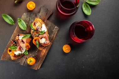 Şarabın hazır. Prosciutto, vişneli domates ve fesleğen yapraklı krem peynirli. metin için yer, üst görünüm.