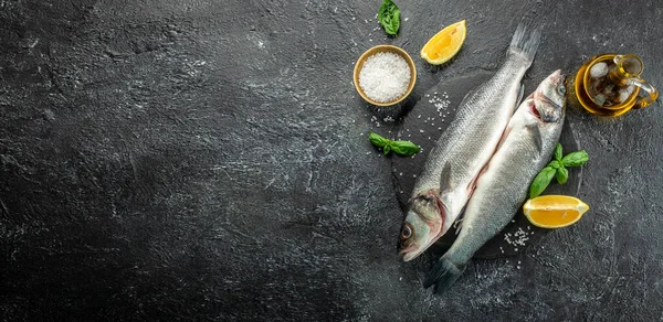 Fresh raw seabass fish on a dark background, Long banner format. top view,