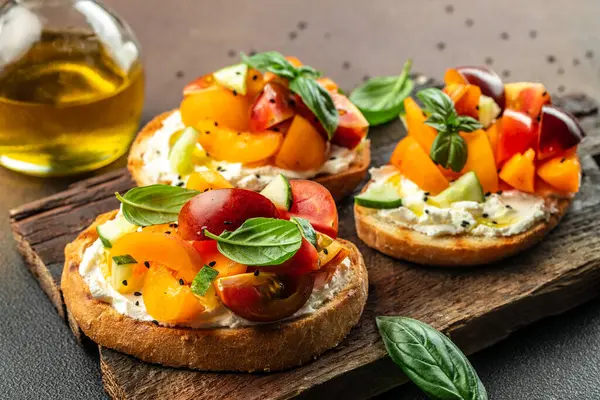 Toast with cream cheese, peaches, tomatoes and green basil leaves. Healthy summer appetizer or snack,