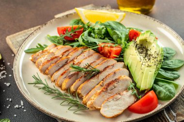 Taze yeşil salata ızgara tavuk filetosu, domates, avokado, açık arkaplanda limon. Diyet Konsepti. Üst görünüm kopyalama alanı,