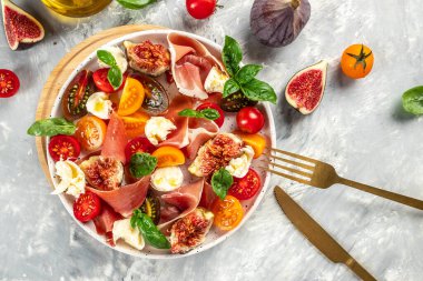 İncirli taze salata, mozzarella, incir, prosciutto taze fesleğen yaprağı ve domates sağlıklı ve dengeli yemek kavramı. metin için yer, üst görünüm,