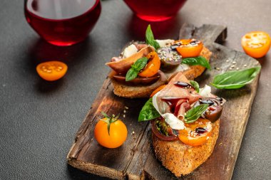 Prosciutto, vişneli domates ve fesleğen yapraklı krem peynir. Antipasto sandviç mezesi,