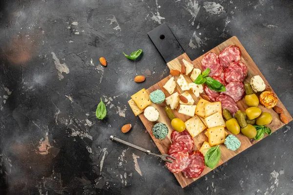 Koyu taş arka planda salam, peynir, ekmek ve zeytin kesme tahtası. afiş, menü, metin için tarif yeri, üst görünüm.