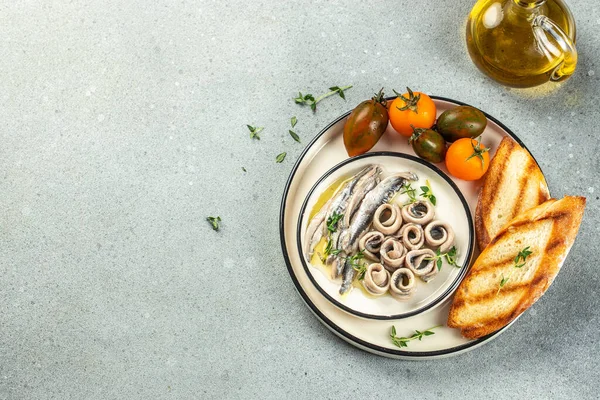 Marinated anchovies in vinegar with olive oil on a light background top view. place for text,