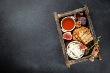 Lezzetli incir, tost, krem peynir, ahşap kutuda ceviz ve bal içeren kompozisyon. Üst Manzara. metin için yer,