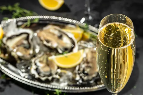 fresh oysters and lemons in bowl near champagne glasses. banner, menu, recipe place for text.